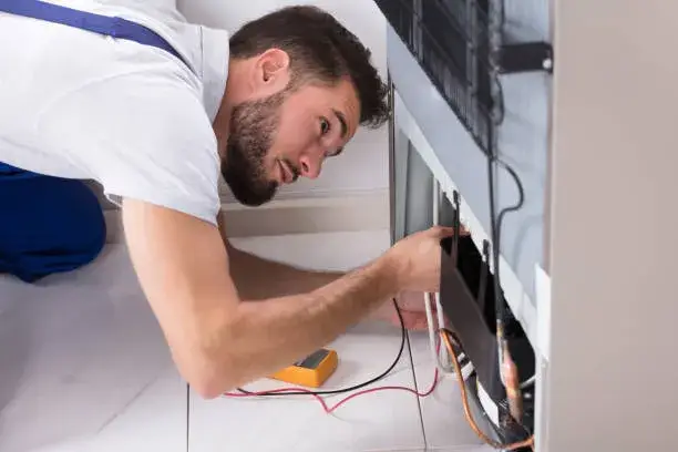 Electrician repairs an electric refrigerator.